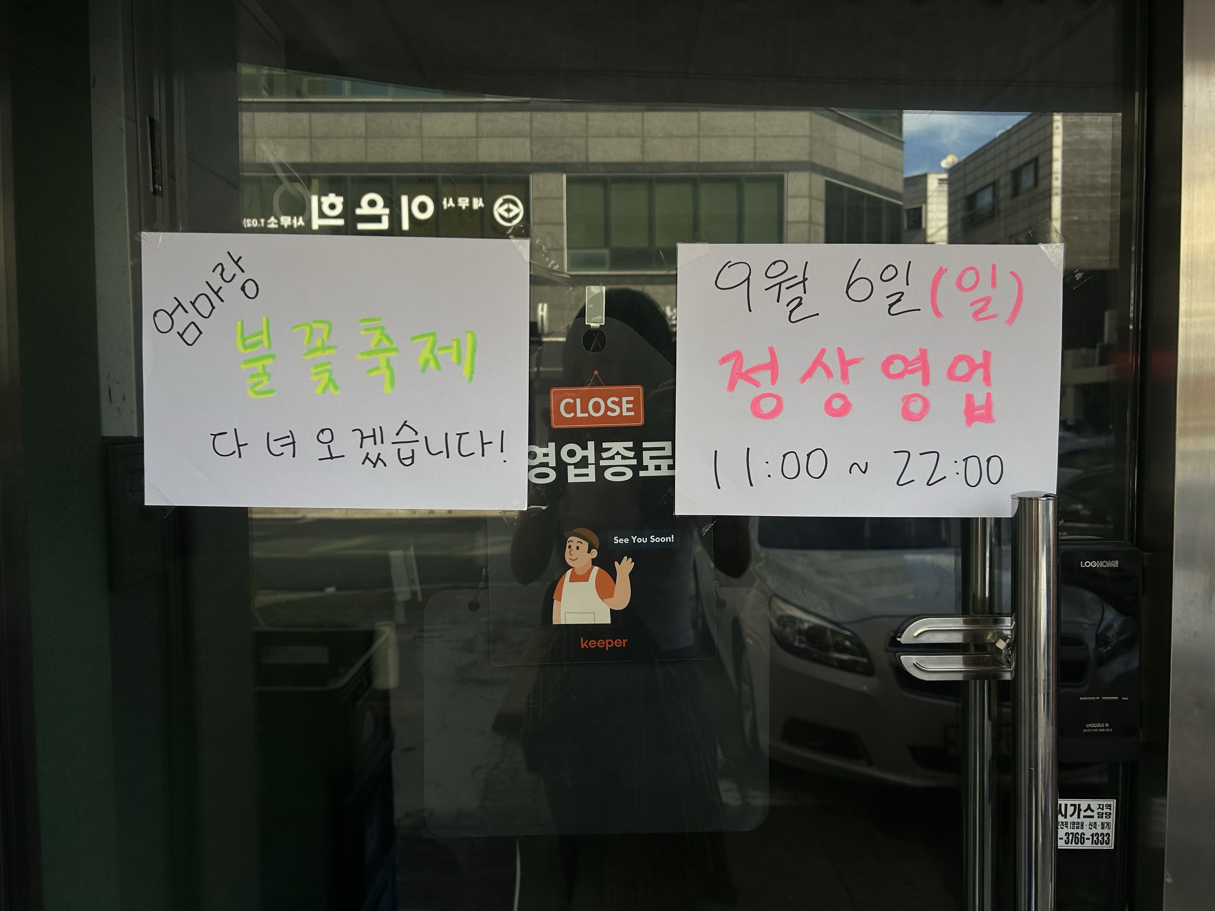 가게 유리문에 붙은 '엄마랑 불꽃축제 다녀오겠습니다' 손글씨 팻말